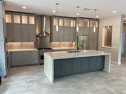 Modern kitchen with gray cabinetry, waterfall island, pendant lights, and quartz countertops