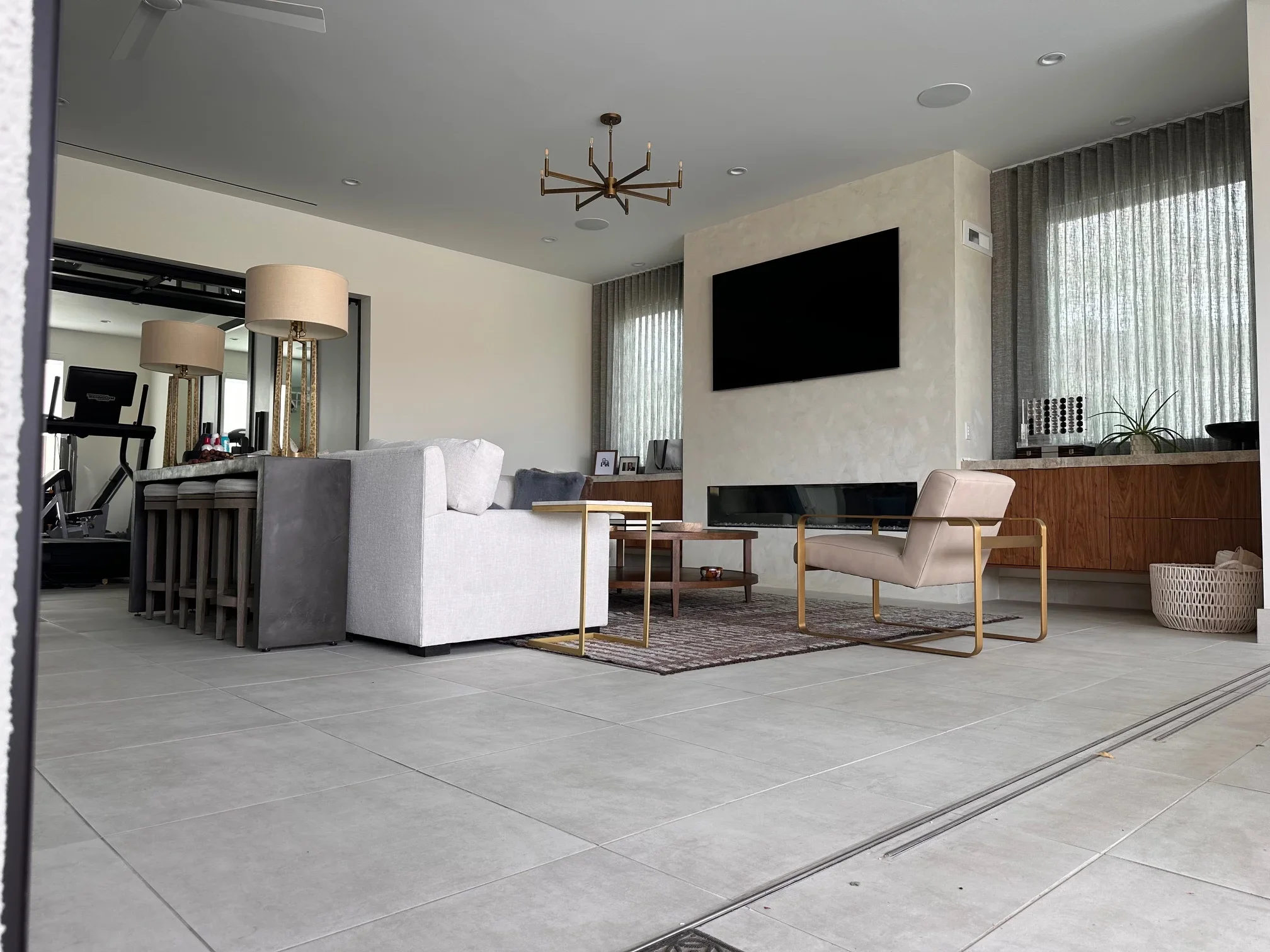 Modern living room with concrete floors, white sofa, wood cabinetry, and mounted TV on accent wall