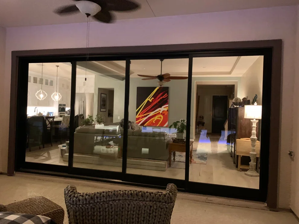 Five-panel black aluminum sliding glass doors with clear glass panes opening to modern interior spaces