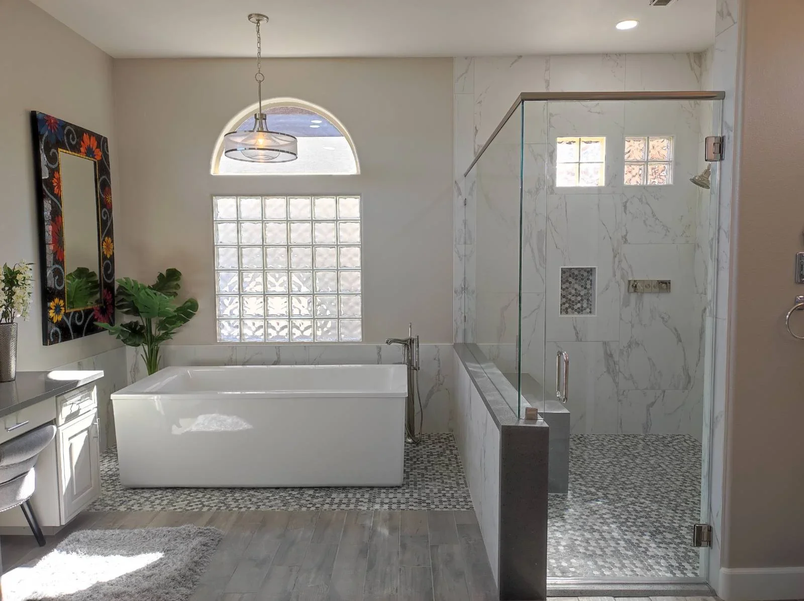 Master bathroom with white soaking tub, marble tile shower enclosure, and mosaic tile flooring