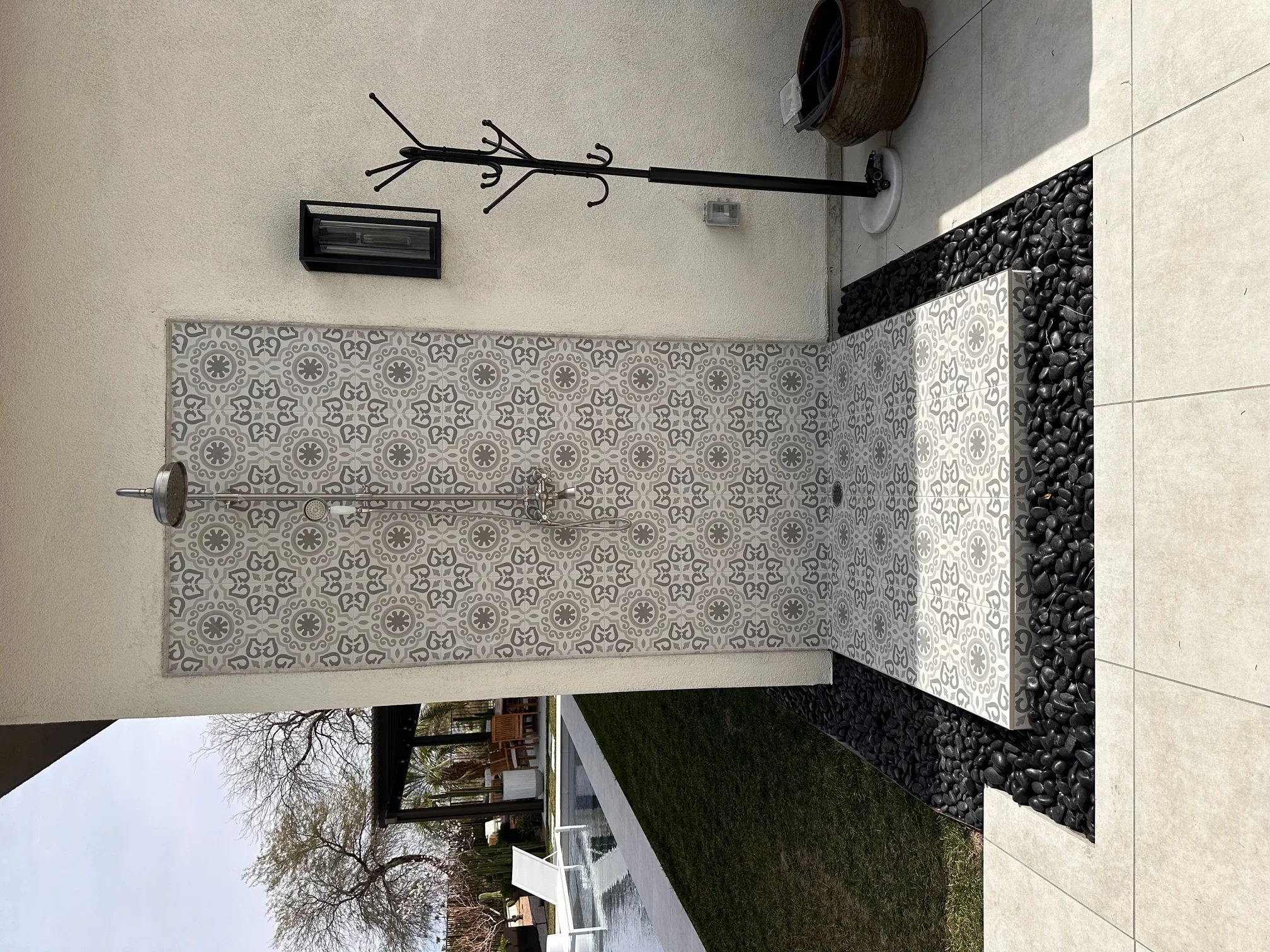 Geometric patterned tile shower with gray and white design, chrome fixtures, and glass enclosure