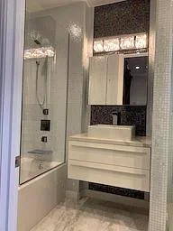 Modern bathroom with floating vanity, subway tile, frameless shower, and concrete flooring