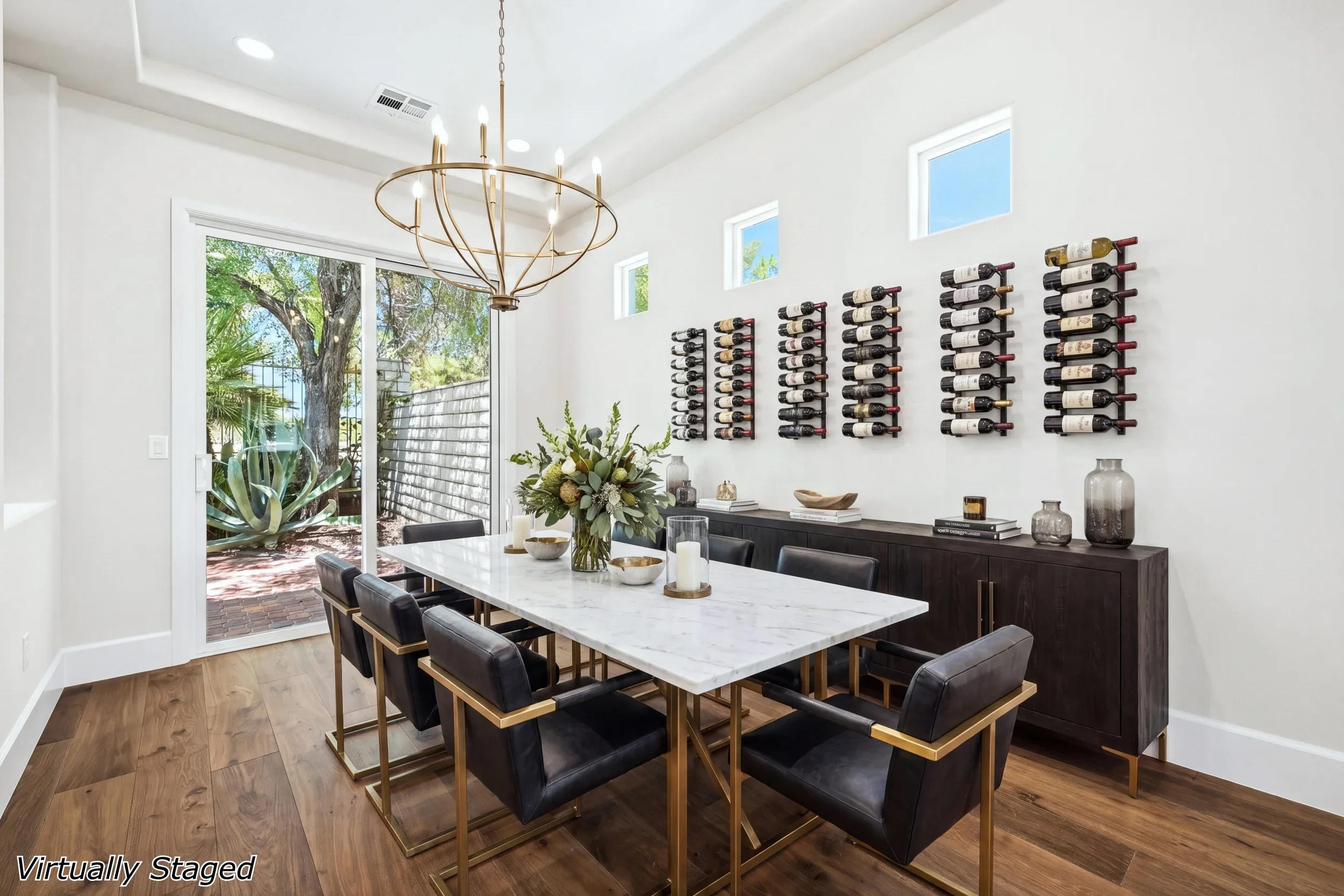 Modern dining room with built-in wine storage, marble table, brass chandelier, and glass patio doors
