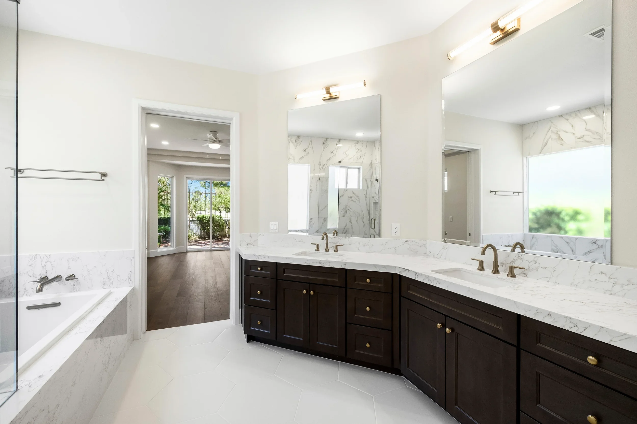 Master bathroom with marble countertops, dual sinks, dark cabinetry, and glass shower enclosure