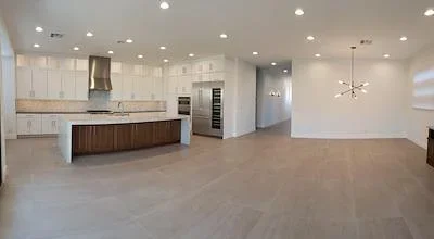 Open concept kitchen with white cabinets, stainless appliances, and polished concrete flooring