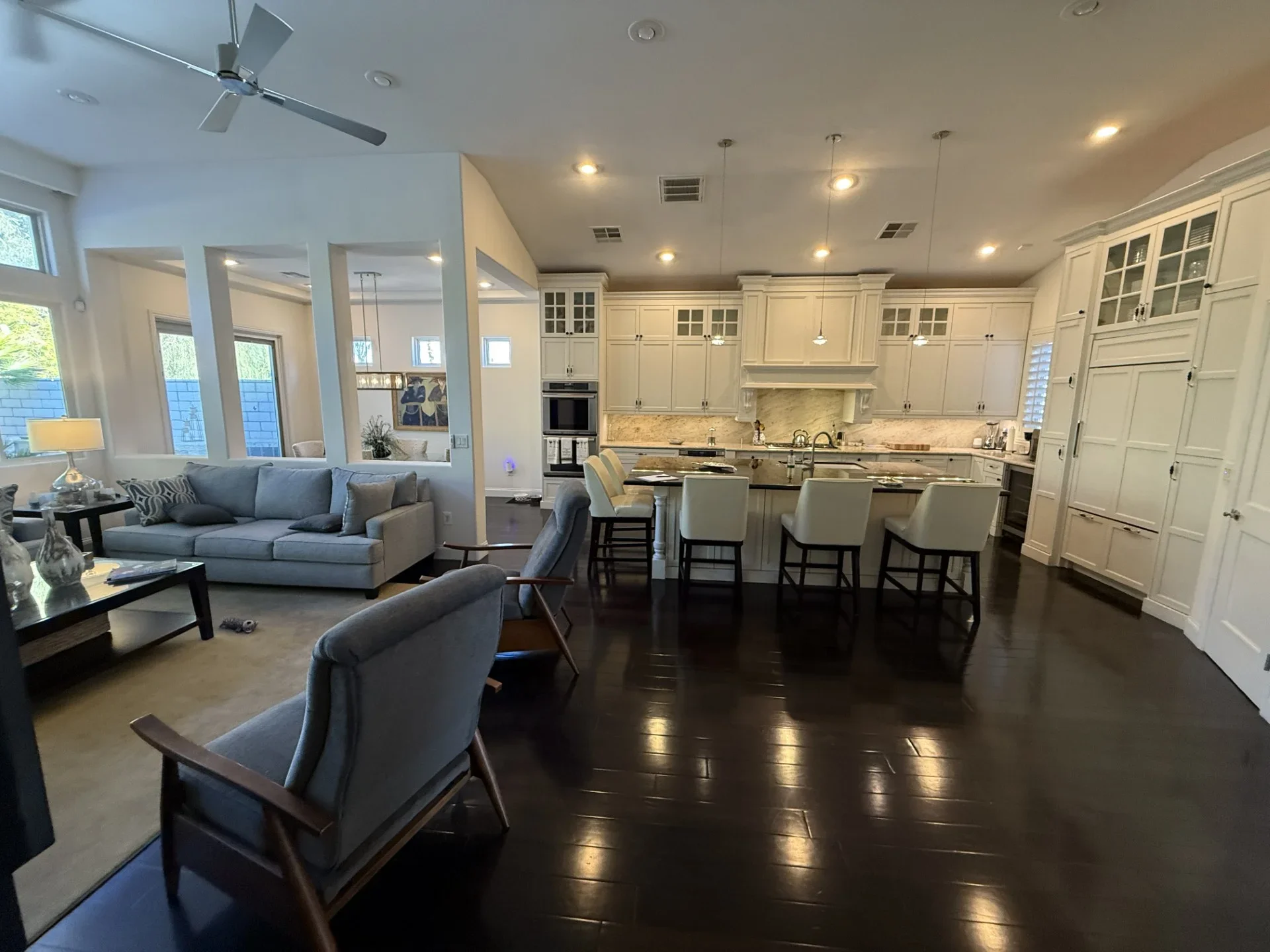 Open concept kitchen with cream cabinetry, marble backsplash, island seating, and dark hardwood floors