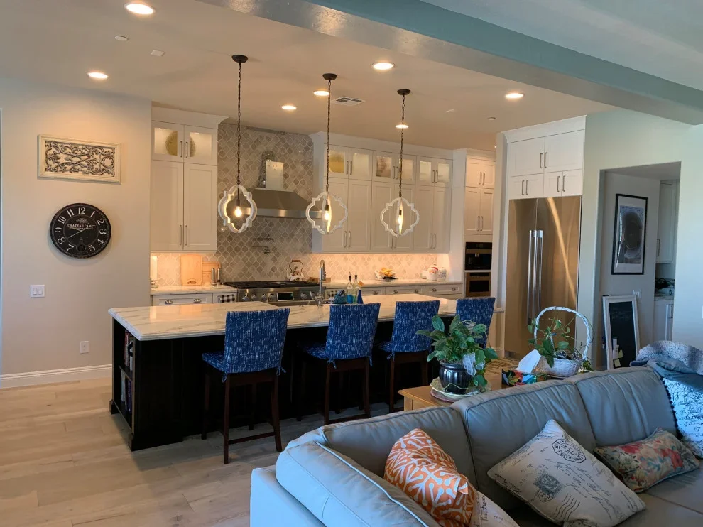Modern kitchen with white cabinets, quartz island, stainless appliances, and pendant lights