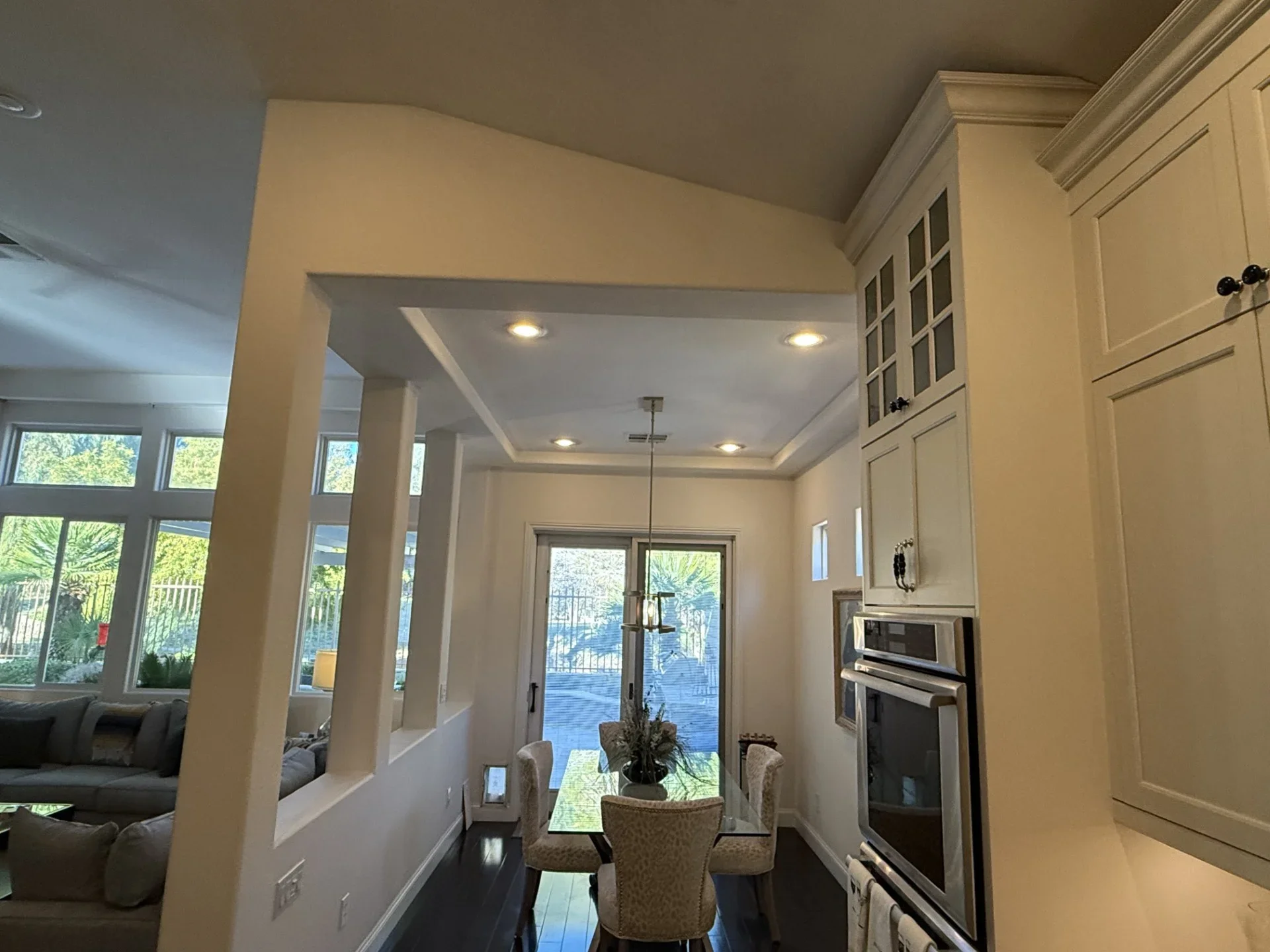 Modern kitchen with white cabinetry, stainless steel appliances, coffered ceiling, and open dining area