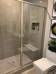 Frameless glass shower enclosure with subway tile walls and built-in bench seat