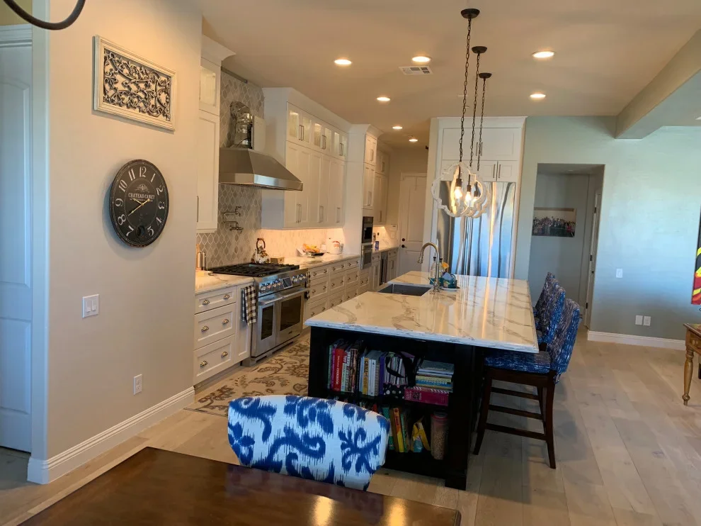 Modern kitchen with white cabinets, marble island, stainless steel appliances, and pendant lights