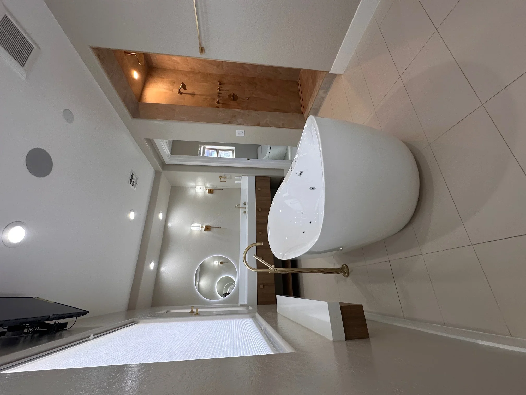 Modern bathroom with freestanding tub, ceramic tile, copper ceiling soffit, and frameless shower