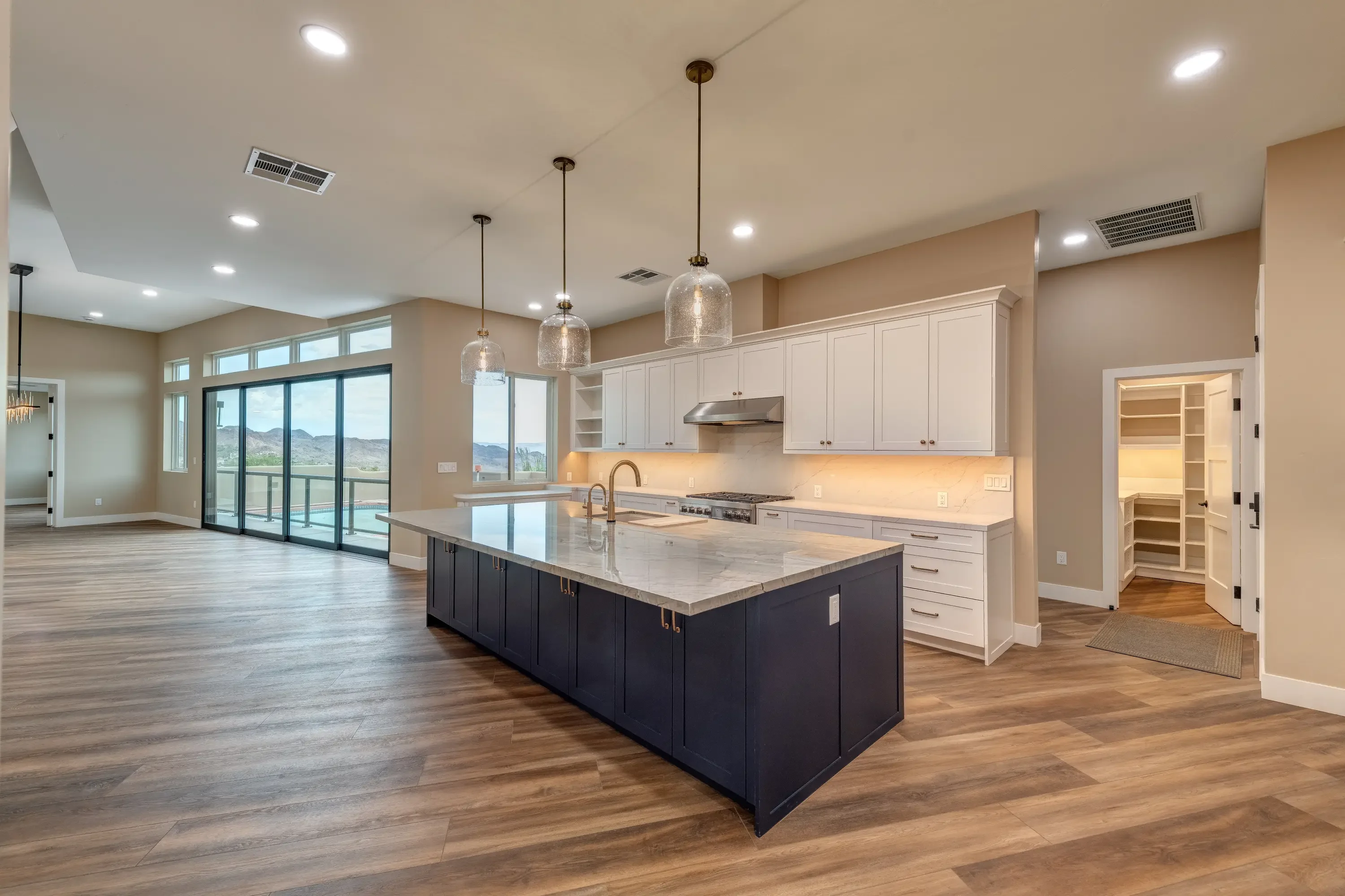 Modern kitchen with white cabinets, dark island, quartz counters, and wood flooring