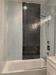 Glass shower enclosure with white subway and dark charcoal tile walls, chrome fixtures