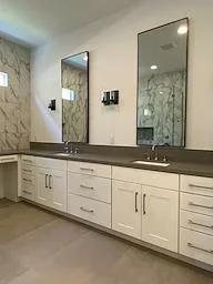 Double vanity with white cabinets, dark countertop, and framed mirrors in modern bathroom