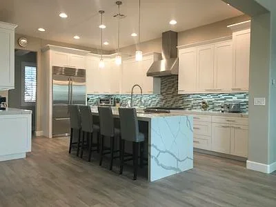 Modern kitchen with white cabinets, marble island, stainless appliances, and geometric tile backsplash