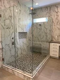 Marble tile walk-in shower with glass enclosure and patterned floor tile in renovated bathroom