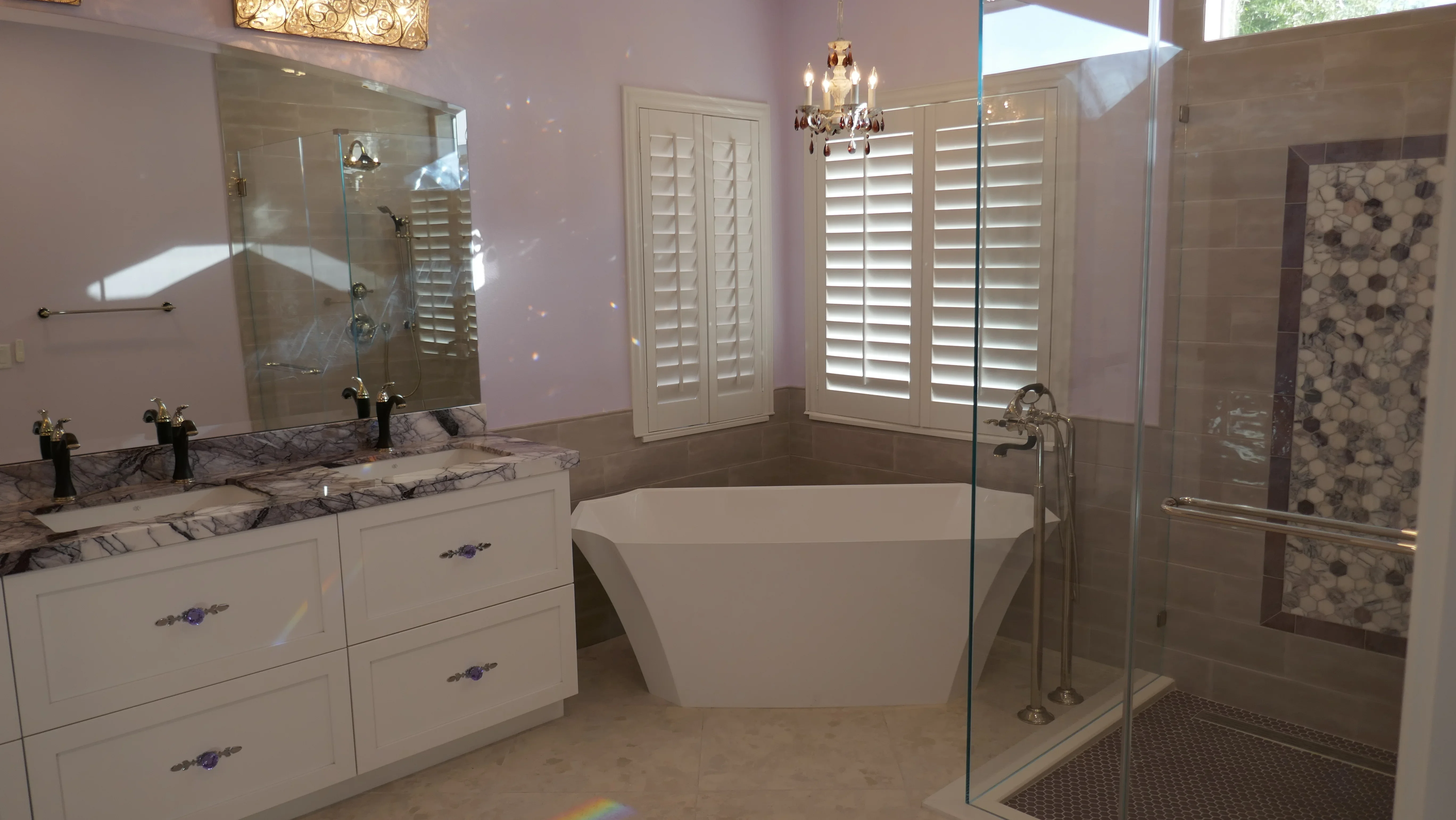 Master bathroom with freestanding tub, frameless shower, marble vanity, and white cabinetry