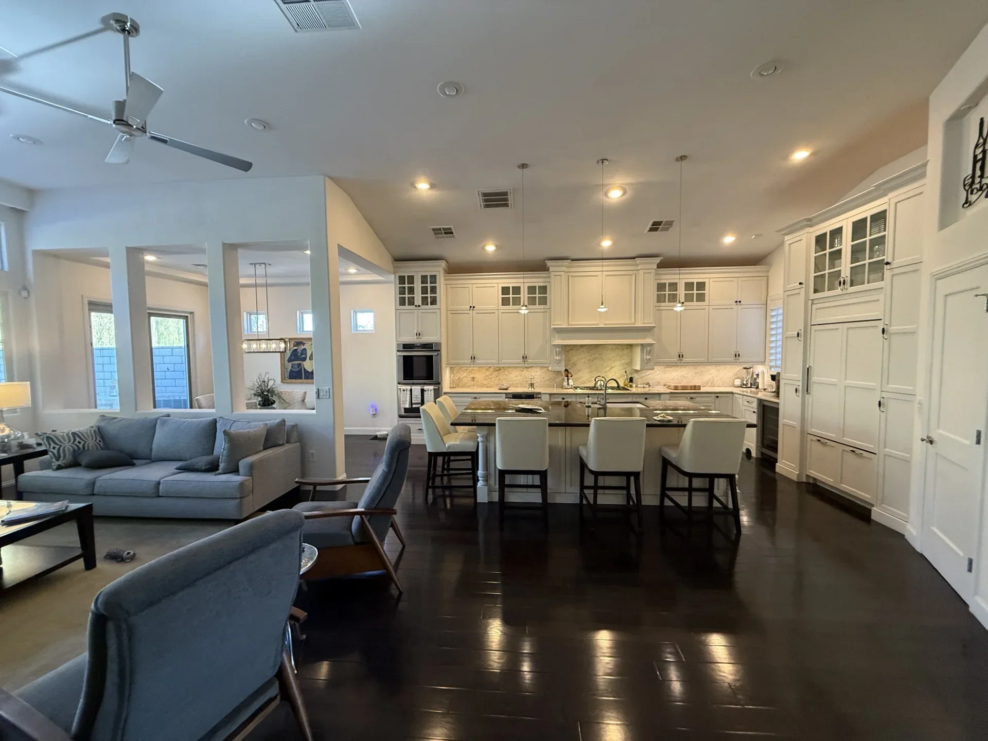 Open concept kitchen with cream cabinetry, granite counters, island seating, and dark hardwood floors