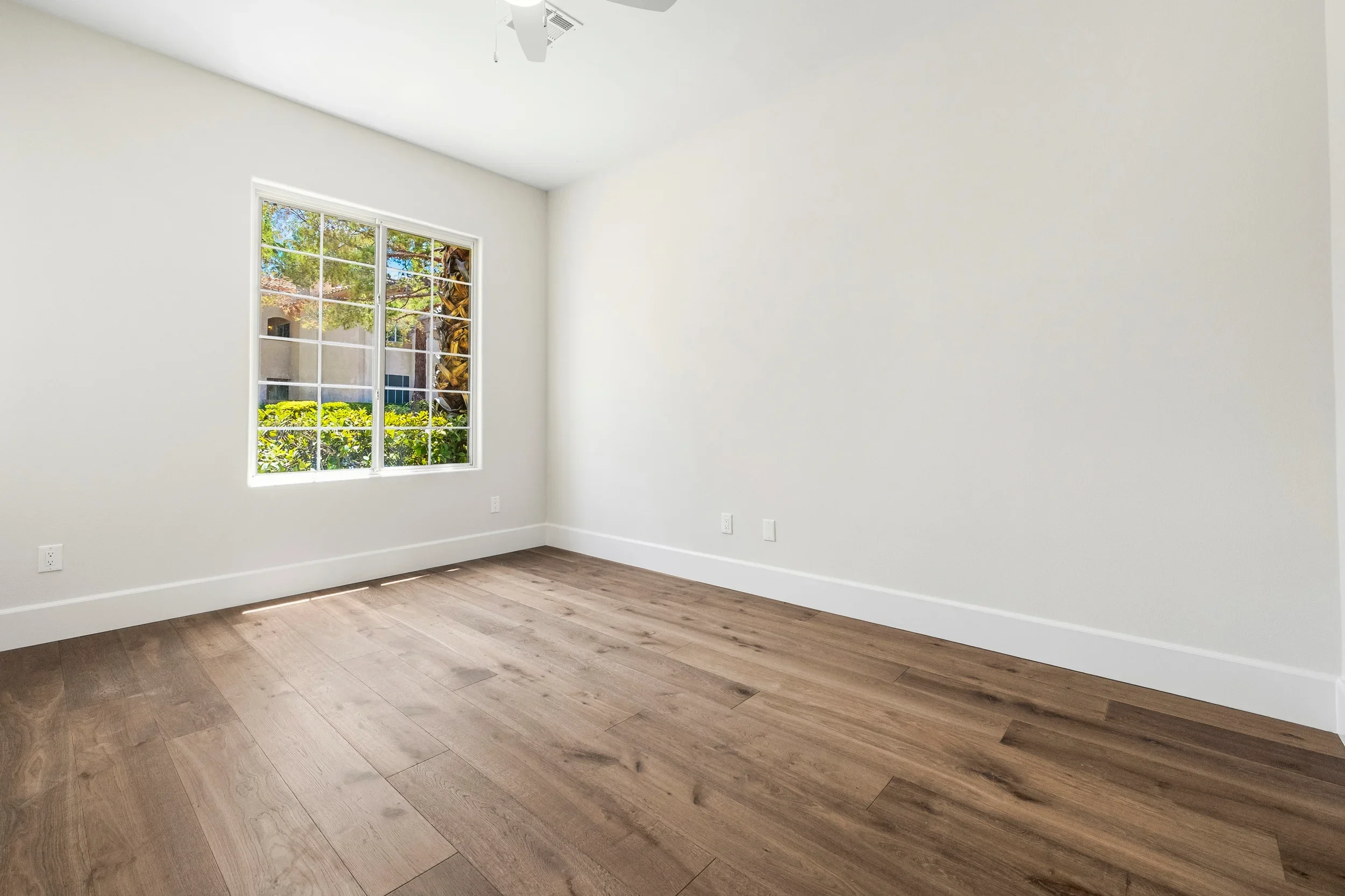 Bright room with engineered hardwood flooring, white walls, trim, and multi-pane windows