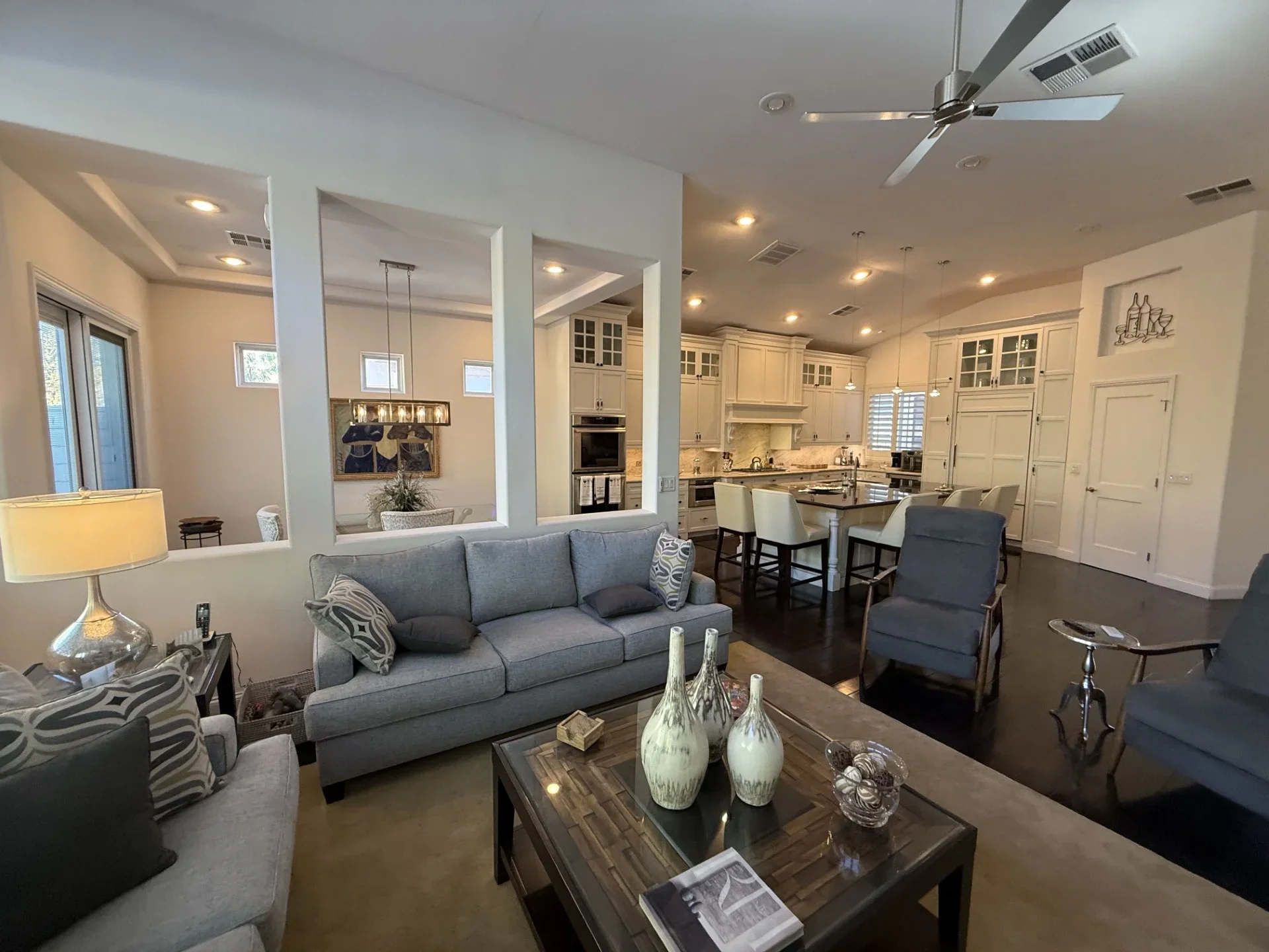 Open concept living room and kitchen with gray sofa, island, custom white cabinetry, and recessed lighting