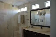 Modern bathroom with frameless glass shower, dark vanity, quartz countertop, and large mirror
