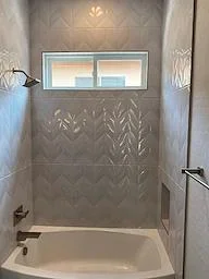 Bathroom shower with herringbone tile pattern, soaking tub, and transom window