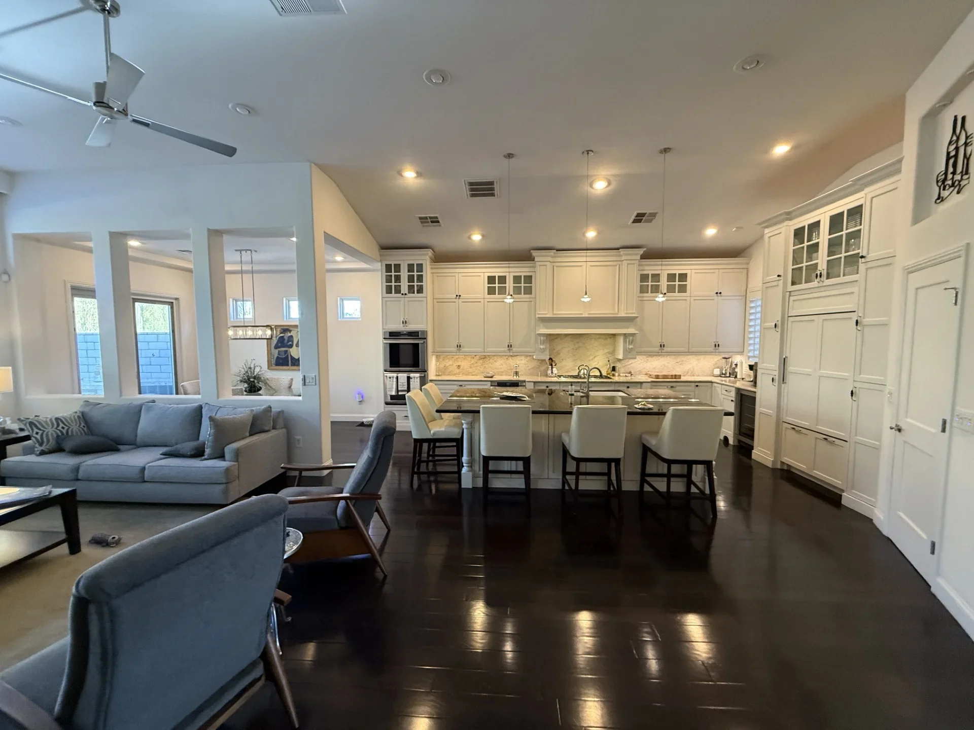 Cream cabinetry, marble backsplash, stainless steel appliances, island seating, dark hardwood flooring