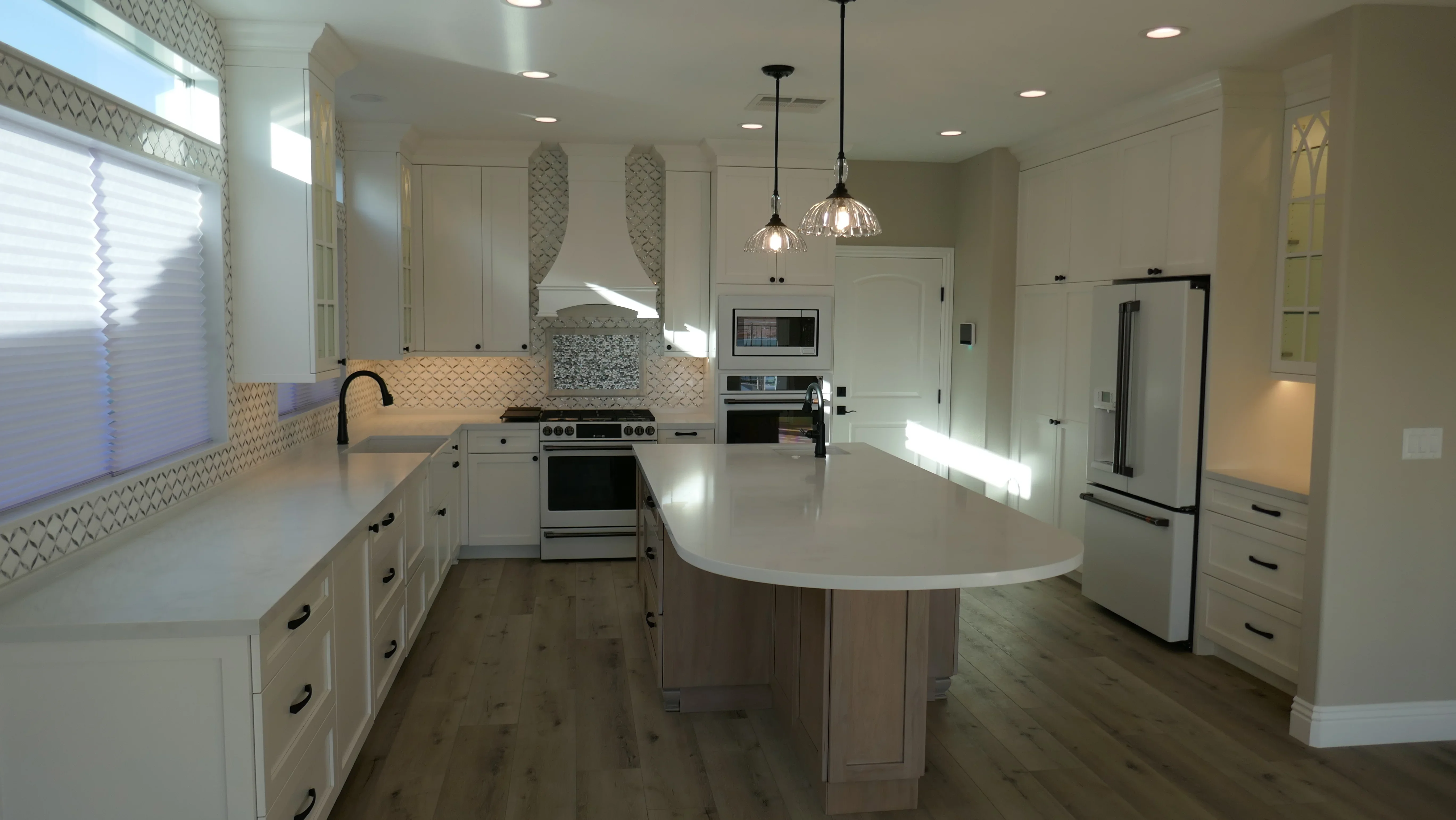 Modern kitchen with white cabinetry, quartz island, geometric tile backsplash, stainless steel appliances