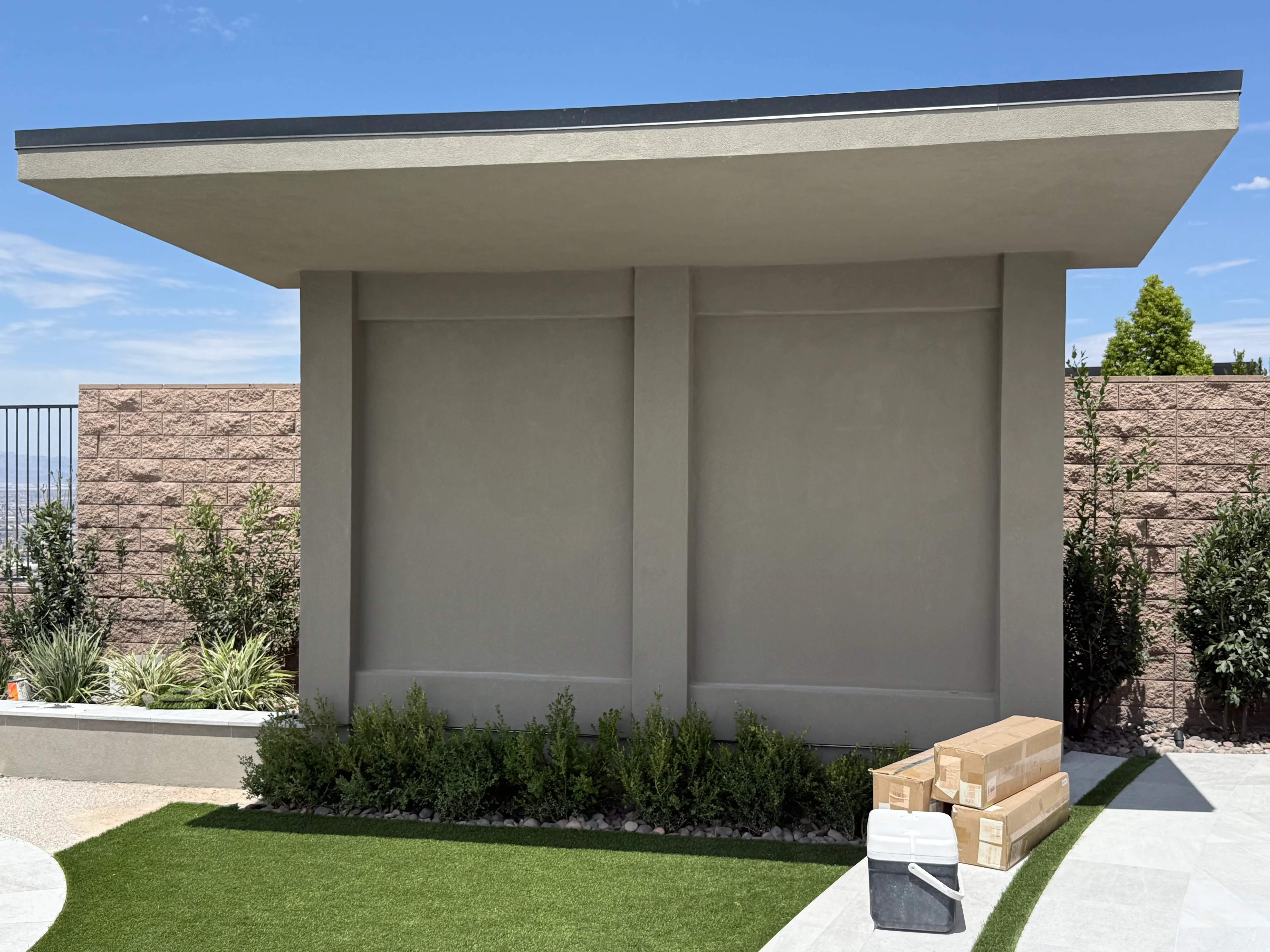 Modern concrete patio with cantilevered roof, stone veneer walls, and integrated landscaping