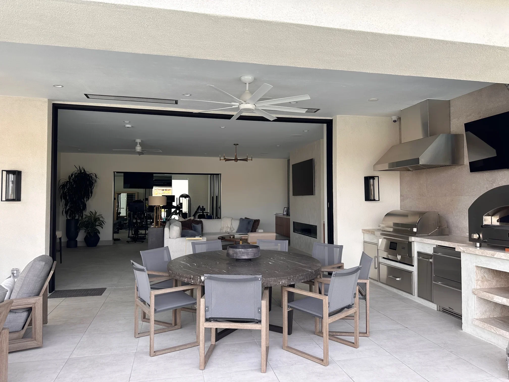 Modern patio with stainless steel outdoor kitchen, pizza oven, and round dining table