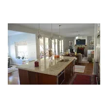Open concept kitchen with granite island, wood cabinetry, and French doors to living area