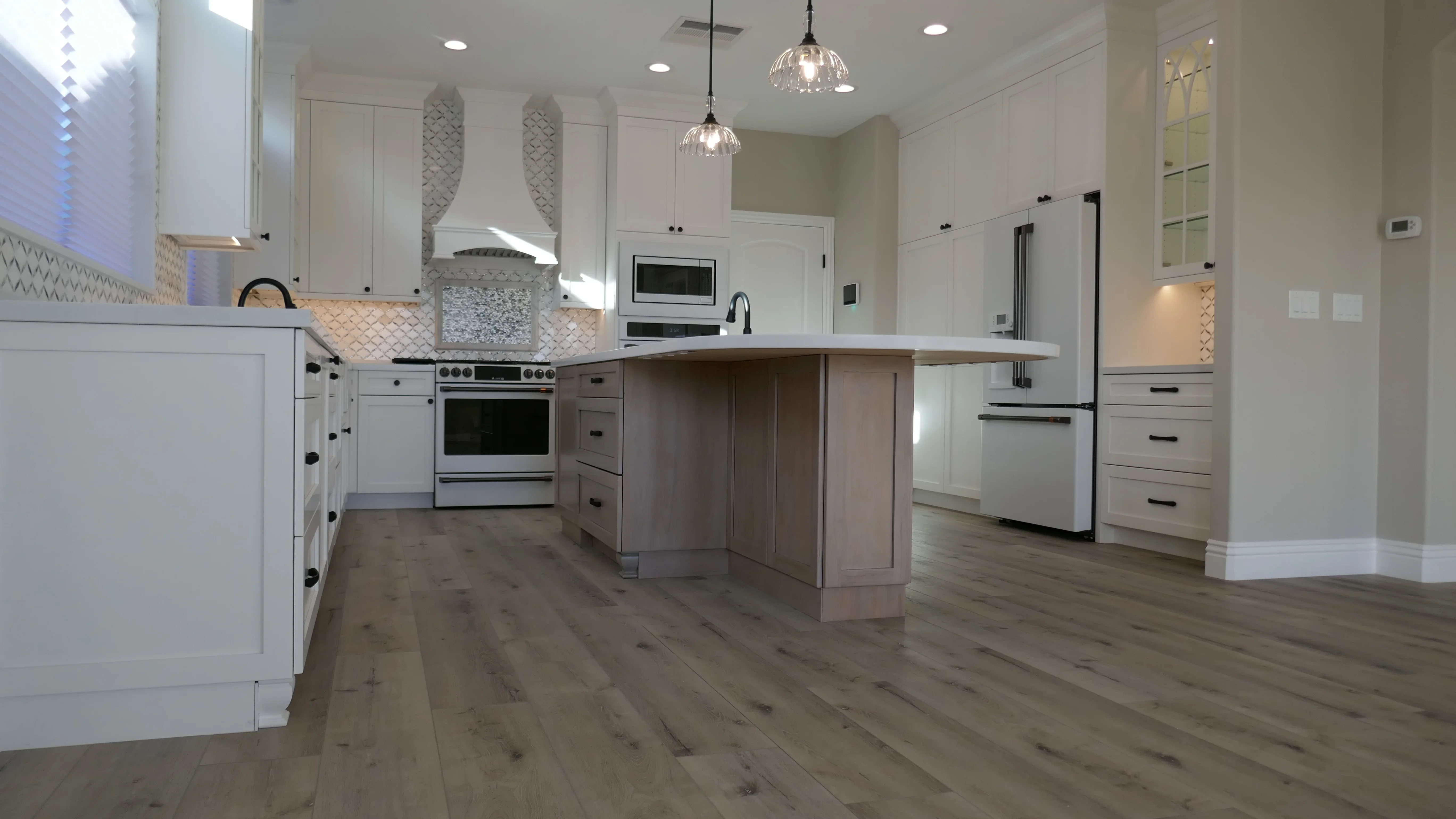Modern kitchen with white cabinets, wood island, geometric backsplash, and stainless steel appliances