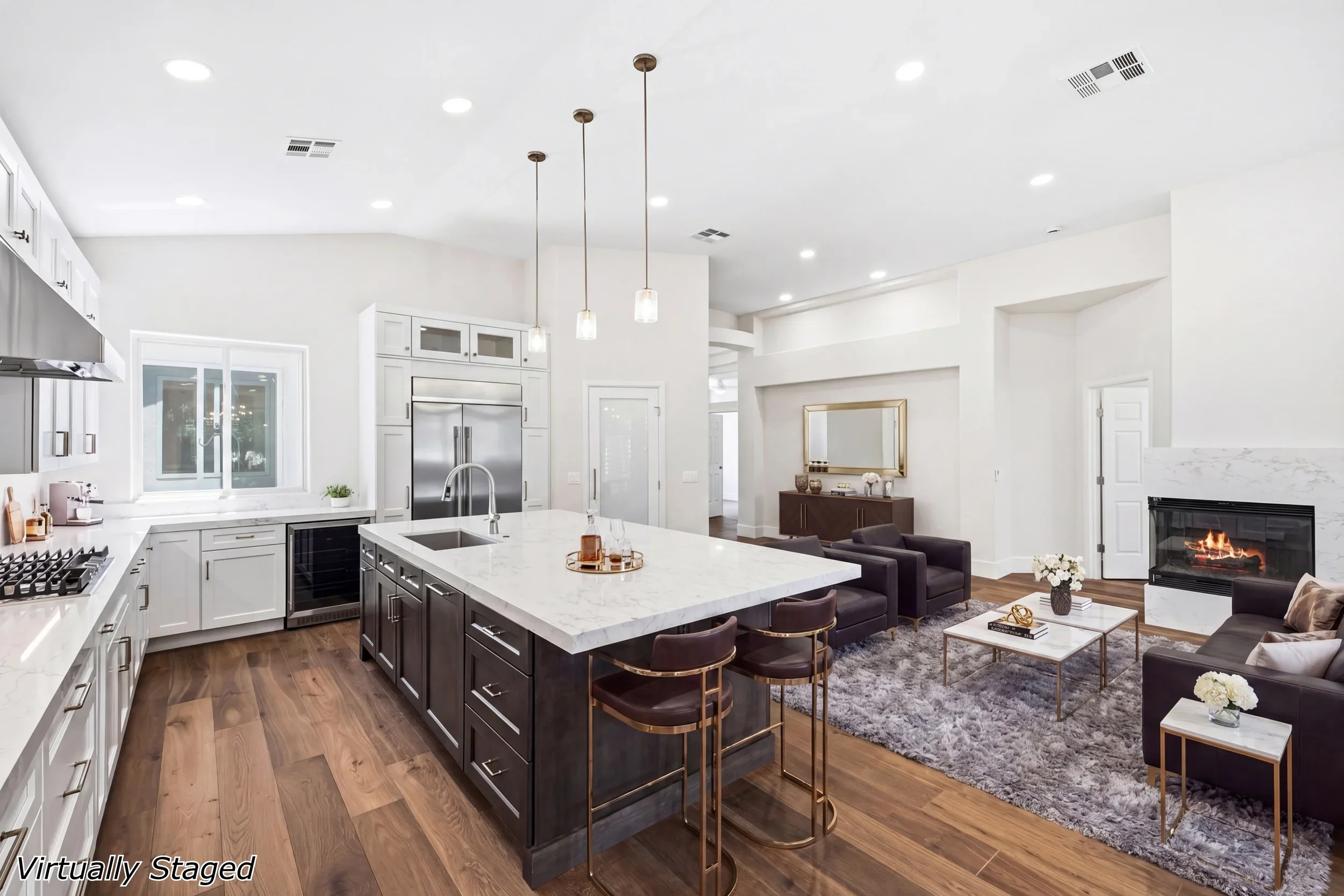 White kitchen with marble island, stainless appliances, dark wood cabinetry, and open living area with fireplace