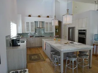White kitchen with marble island, glass cabinets, and stainless steel appliances